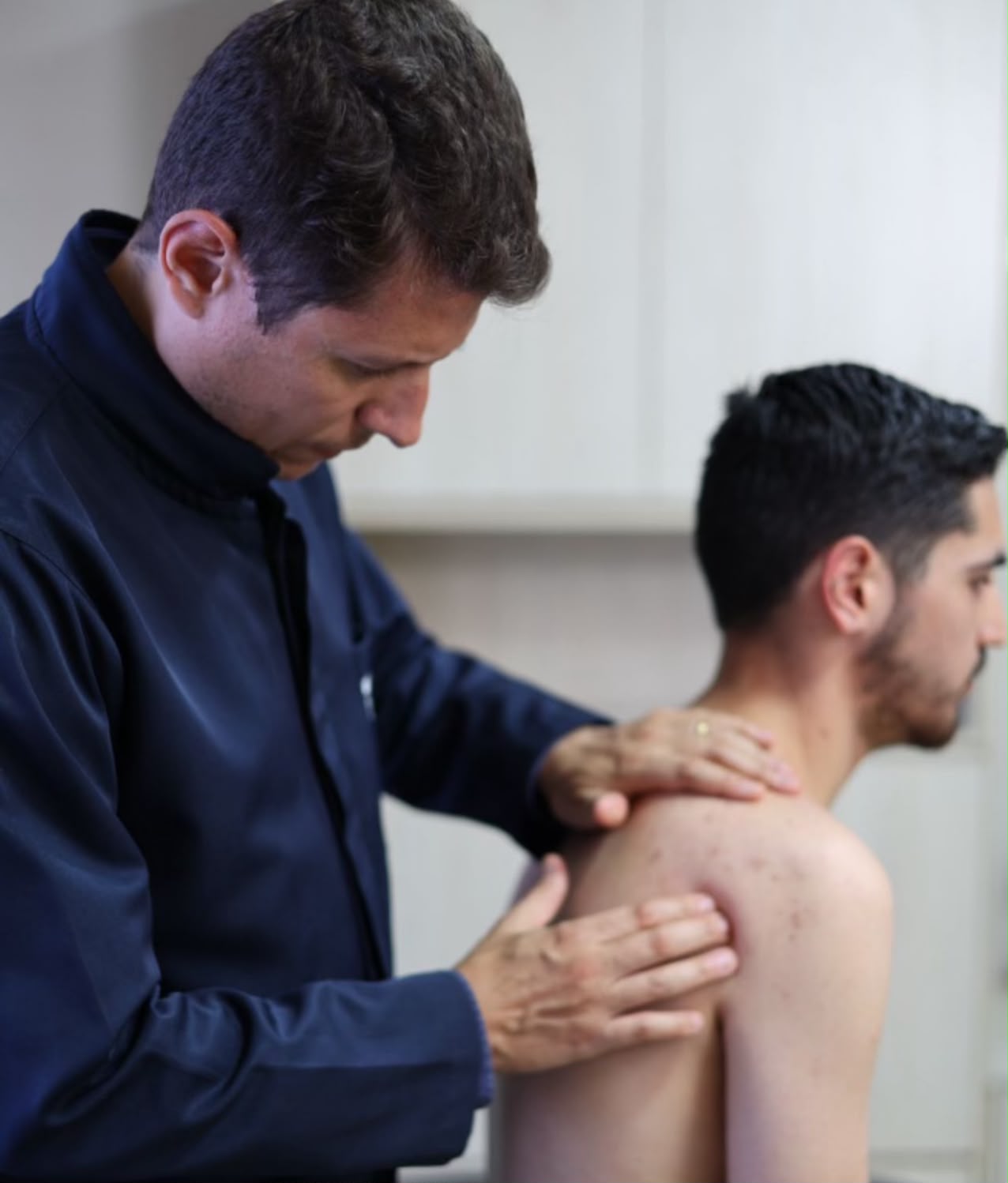 Osteopata realizando massagem nas costas e ombro do paciente